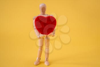 Wooden mannequin holding red heart. Love and passion concept.