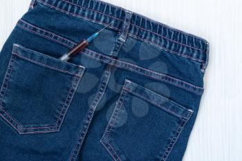 Syringe in the back pocket of blue jeans. Drug and heroine addiction problem among the youth. 