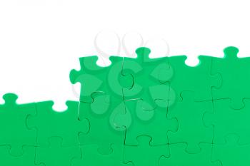 Unfinished green jigsaw puzzle wall. Copy space.