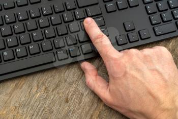 Hand typing on the remote wireless computer keyboard in an office at a workplace 