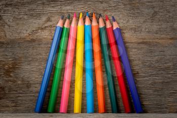 Colored pencil crayons standing on the wooden shelf