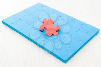 Red color puzzle piece standing out from larger group of blue puzzle pieces. Business concept and ideas branding, different, original.