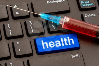Healthcare concept: Syringe with vaccine on the computer keyboard with HEALTH button