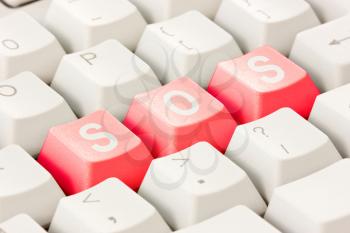 White computer keyboard with red keys arranged in the word SOS. Computer keyboard with SOS keys.