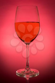 Red wine glass with reflection on red background