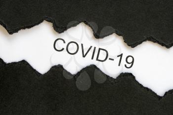 Top view of black torn paper and the word COVID-19 on a white background. Coronavirus, COVID-19, self-quarantine, isolation