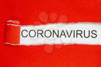 Top view of red torn paper and the text CORONAVIRUS on a white background. Healthcare and medical concept.