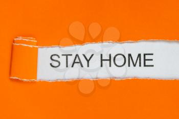 Torn orange paper with words STAY HOME. Stay at home slogan with house and heart inside. Protection campaign or measure from coronavirus, COVID--19. 