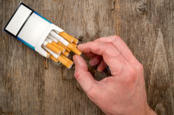 Close-up view of male hand take a cigarette from the pack