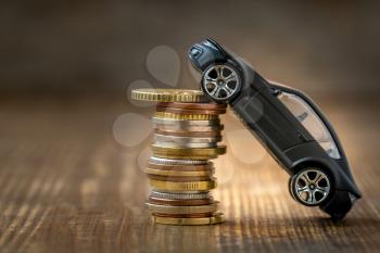 Black car over a lot of stacked coins. Concept for car insurance or buying new car 