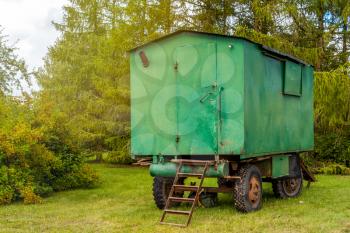 Old green rusty construction camper, trailer, van or wagon. Temporary housing for workers.