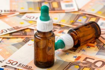 Symbolic picture for high cost of medicaments with medicine bottle on money (50 euro banknotes). Medical concept. 