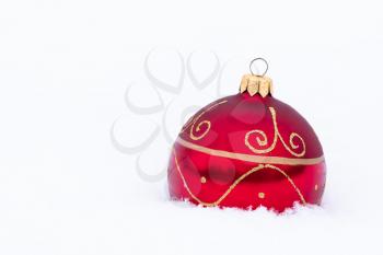 Christmas decoration. Beautiful red Christmas bauble on real snow outdoors. Winter holidays concept