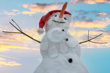 Funny snowman in Santa hat with sky background.