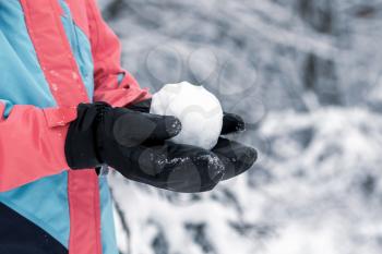 A child holds a snowball in his hands on the street 