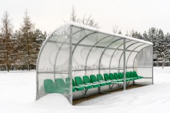 Plastic seats in a winter stadium covered with snow in winter