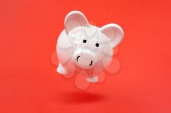 Secure savings. Piggy bank levitating over a red background. Copy space.