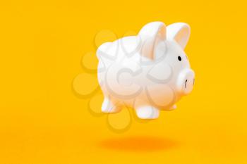 Secure savings. Piggy bank levitating over a yellow background. Copy space.