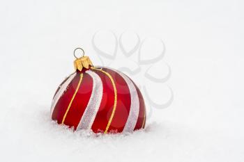 Beautiful red Christmas ball on real snow outdoors. Copy space.