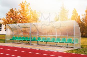 Green chair for spare team near running track on the stadium