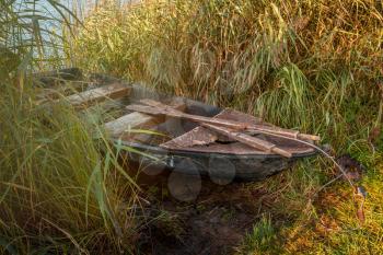 An old abandoned wooden boat left near the lake, used by local people for fishing, boat in poor condition