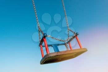 Empty children's swing flies free in the sky.Concept of play, outdoor recreation, entertainment, childhood.