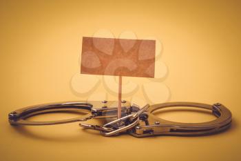 Handcuffs and blank banner mock up on wood stick. Conceptual image.