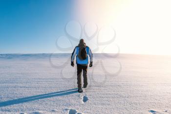 Young man is walking in winter landscape. Walking alone in cold weather.