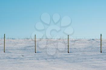 Winter landscape of snow covered fields and wire fence.