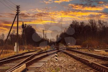 Junction of railways track in trains station against beautiful sunset sky.