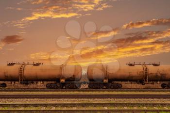 Oil transporter railway carriage. Freight train delivering gasoline in tanks at sunrise.