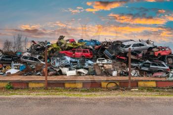 Junkyard with lots of cars located behind the fence, waiting for recycling or destruction