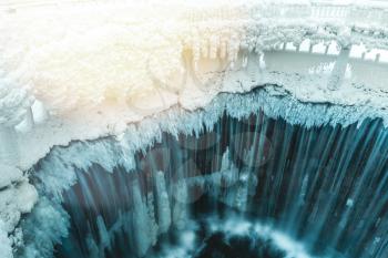 A frozen waterfall with ice and snow on sunlight. Winter background.