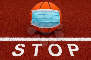 Sign stop and basketball ball with medical mask. Stop sport. Cancellation of sports tournaments.