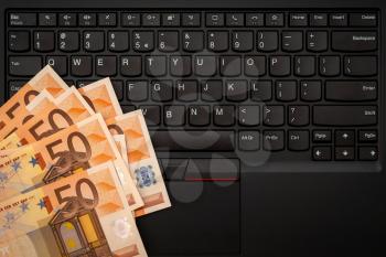 Money cash banknote on laptop keyboard, digital money and e-commerce concept. Top view.