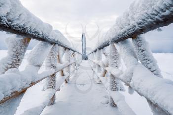 Metal bridge with handrails covered with snow and ice. Extremely cold winter.