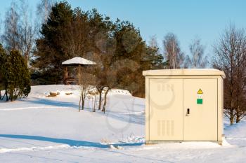 Outdoor electric high voltage distribution cabinet on a sunny winter park