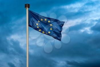 A flag of european union is waving on a background of stormy sky 