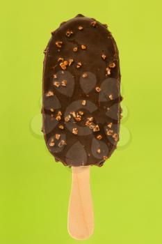 Ice cream popsicle covered with chocolate isolated on green background