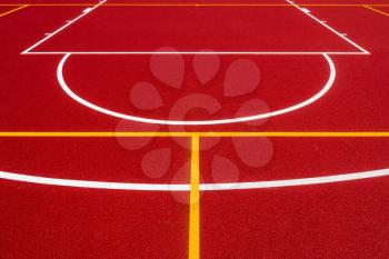 Abstract, red background of newly made outdoor basketball court in park. Visible surface texture, freshly painted lines