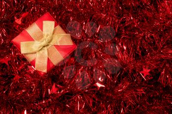 Christmas  gift box on background of shiny red tinsel. Christmas or New year decoration.
