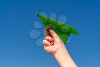 Paper plane in child hand on clear blue sky 