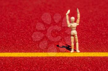 Wooden figure doing exercises on running track. Healthy life concept.