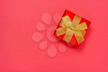 Beautiful christmas gift with golden ribbon isolated on pink paper background. Christmas present background with copy space.