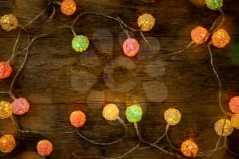 Colorful Christmas lights on wooden planks, top view.