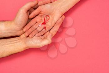 Man holds female hand with a  pink ribbon. Breast cancer awareness, abdominal cancer awareness and October Pink day background , world cancer day.