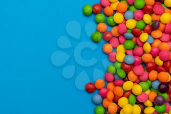 Many colorful candies on blue background, copy space