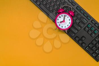Alarm Clock counting at 8AM in the morning with computer keyboard for office starting time concept.