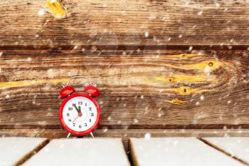 Frozen time. Alarm clock outdoor under falling snow. Extreme weather situation. Winter time.