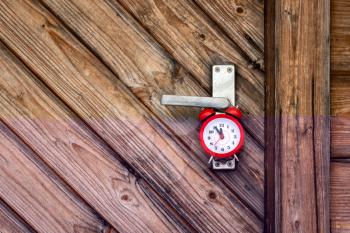 Red alarm clock hanging on the wooden door handle